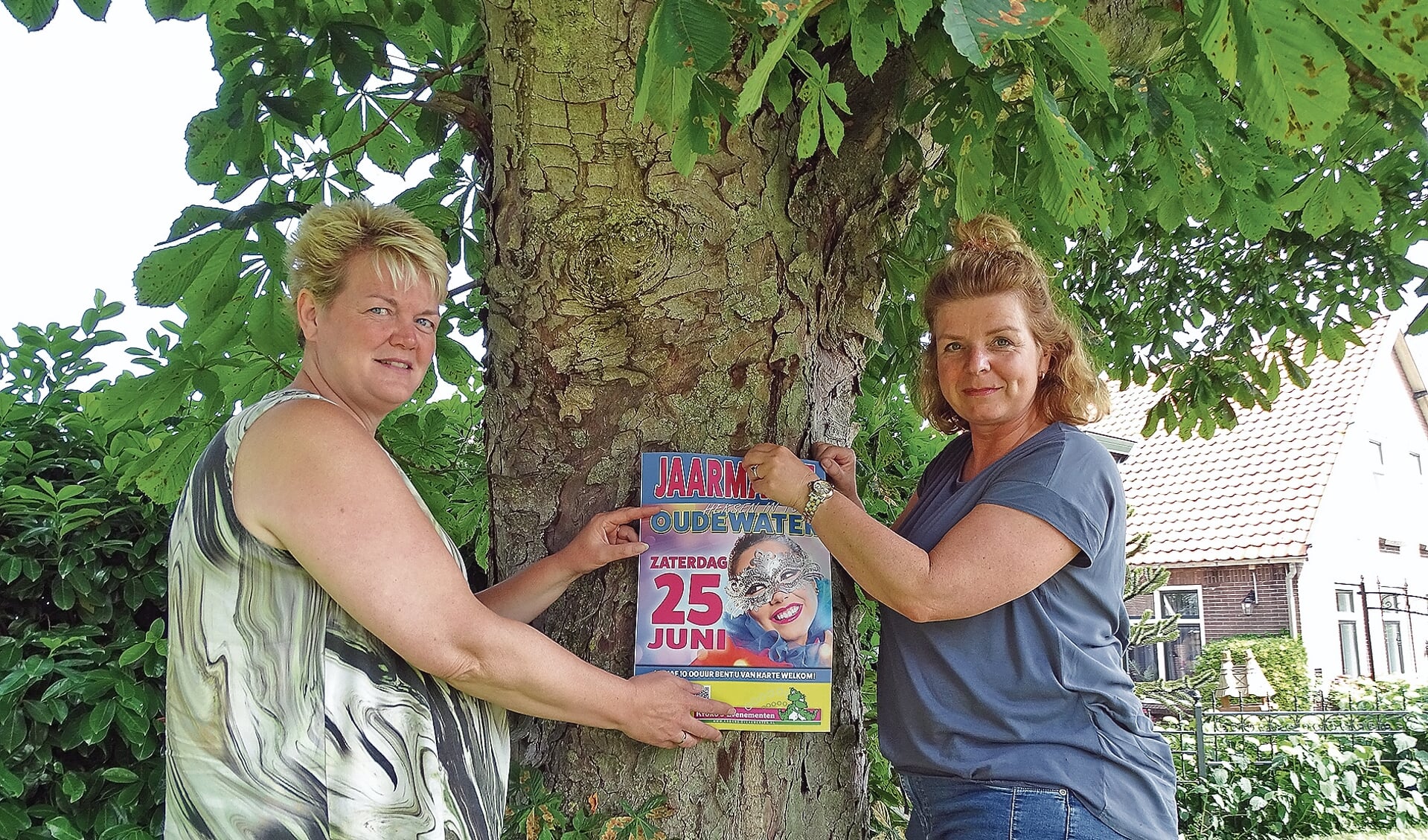 Carolien Sleeuwenhoek (li) en Joanne Vlielandprikken een affiche op de boom.