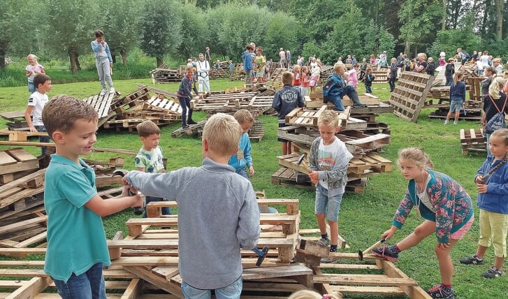 Kinderen kiezen een stapel pallets en bouwen hier,met hulp van ouders, een mooie creatie van.