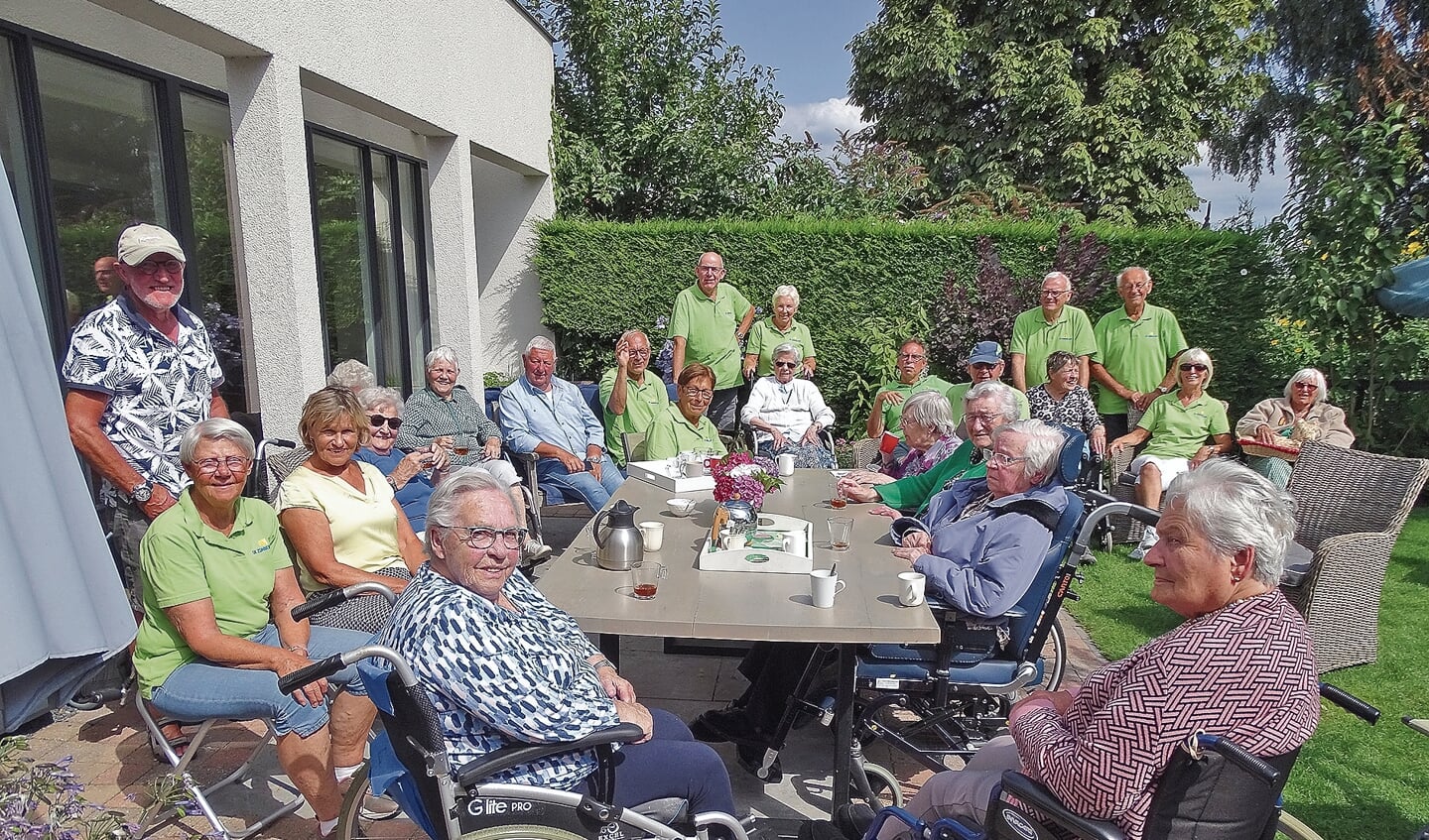 De hele groep rolstoelgebruikers en hun vrijwilligersin de tuin bij Coby van Leeuwen.