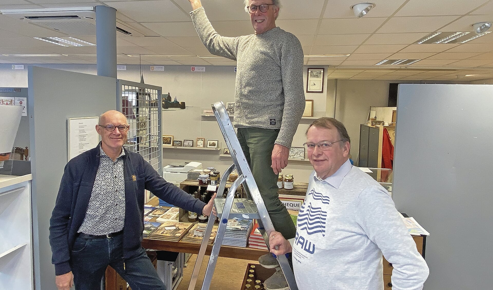 Peter Gruters op de trap laat de LED-verlichting zien, waar het om gaat,Haike Mintjes (rechts) en Peter Versloot (links) staan ervoor.