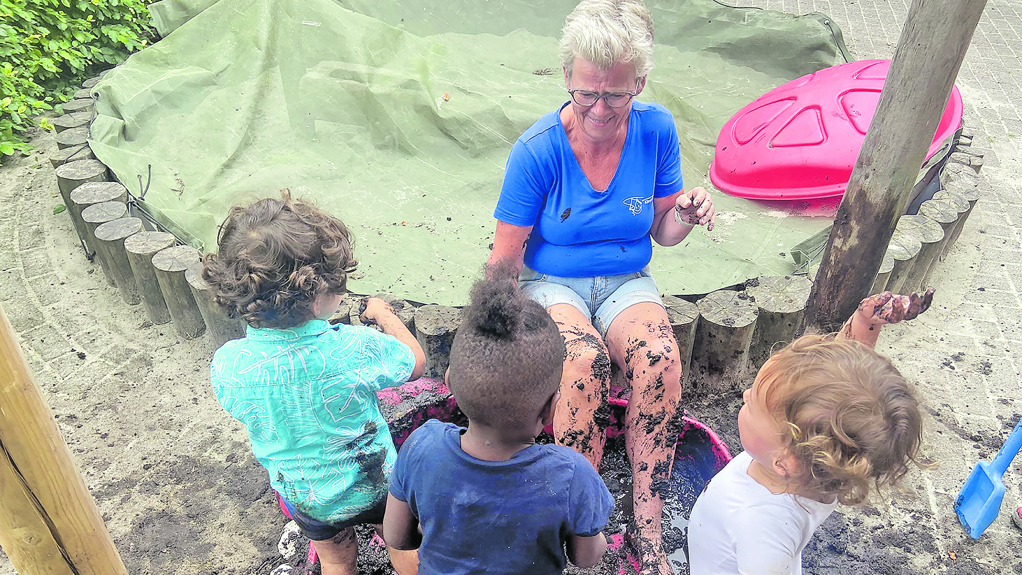 Juf Elly doet de kinderen voor wat je met modder kunt doen.