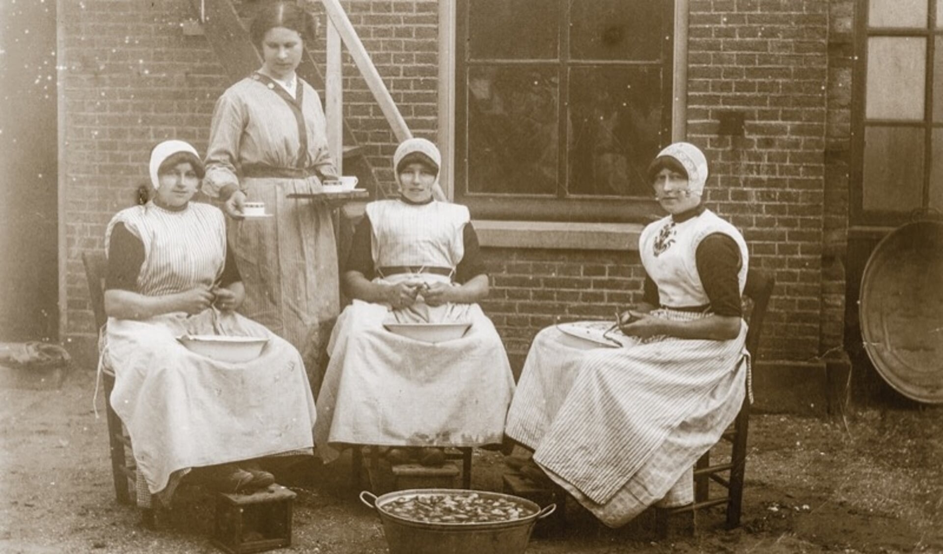 Urker dienstmeisjes schillen aardappels in een koloniehuis.