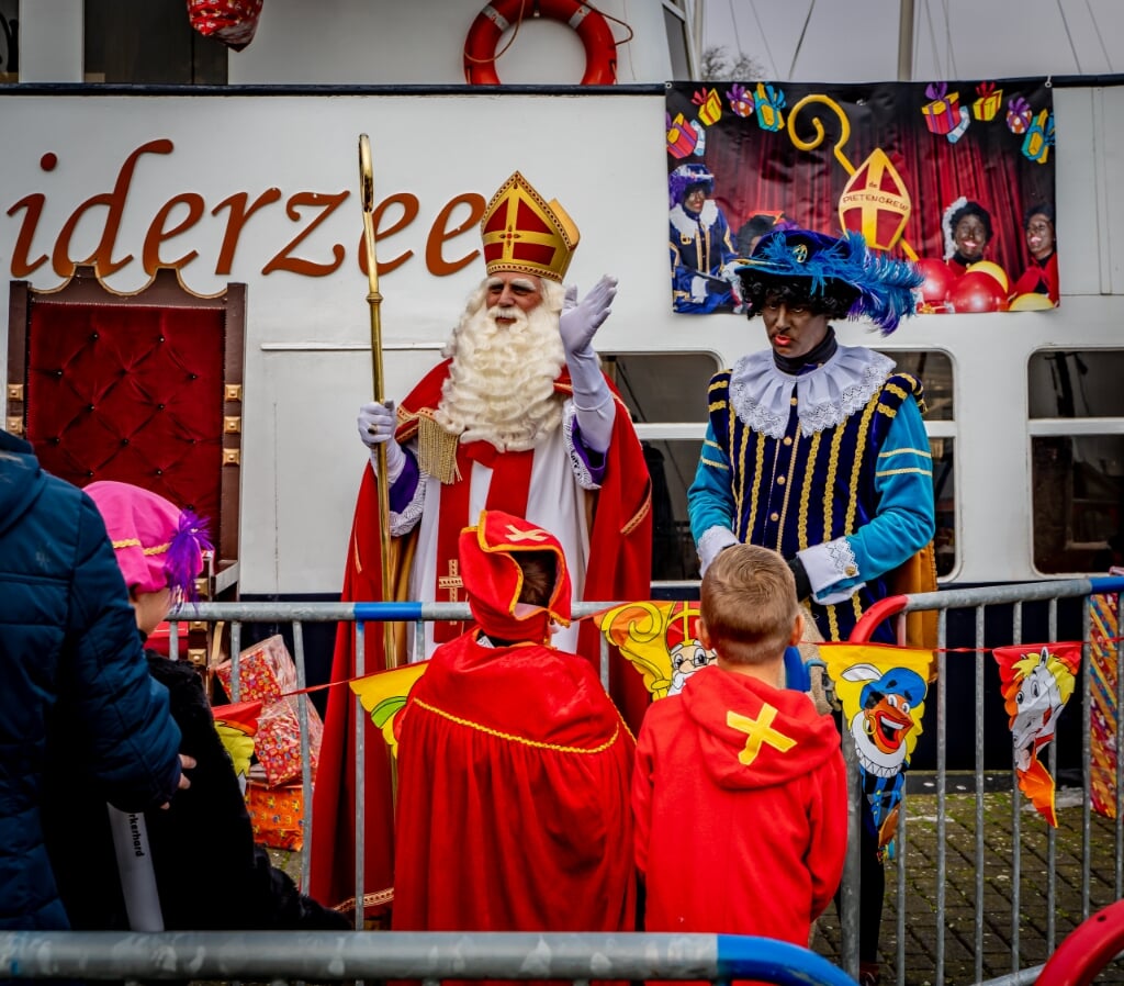 n Twee mini-sinterklazen kijken vol ontzag naar de echte Sinterklaas.