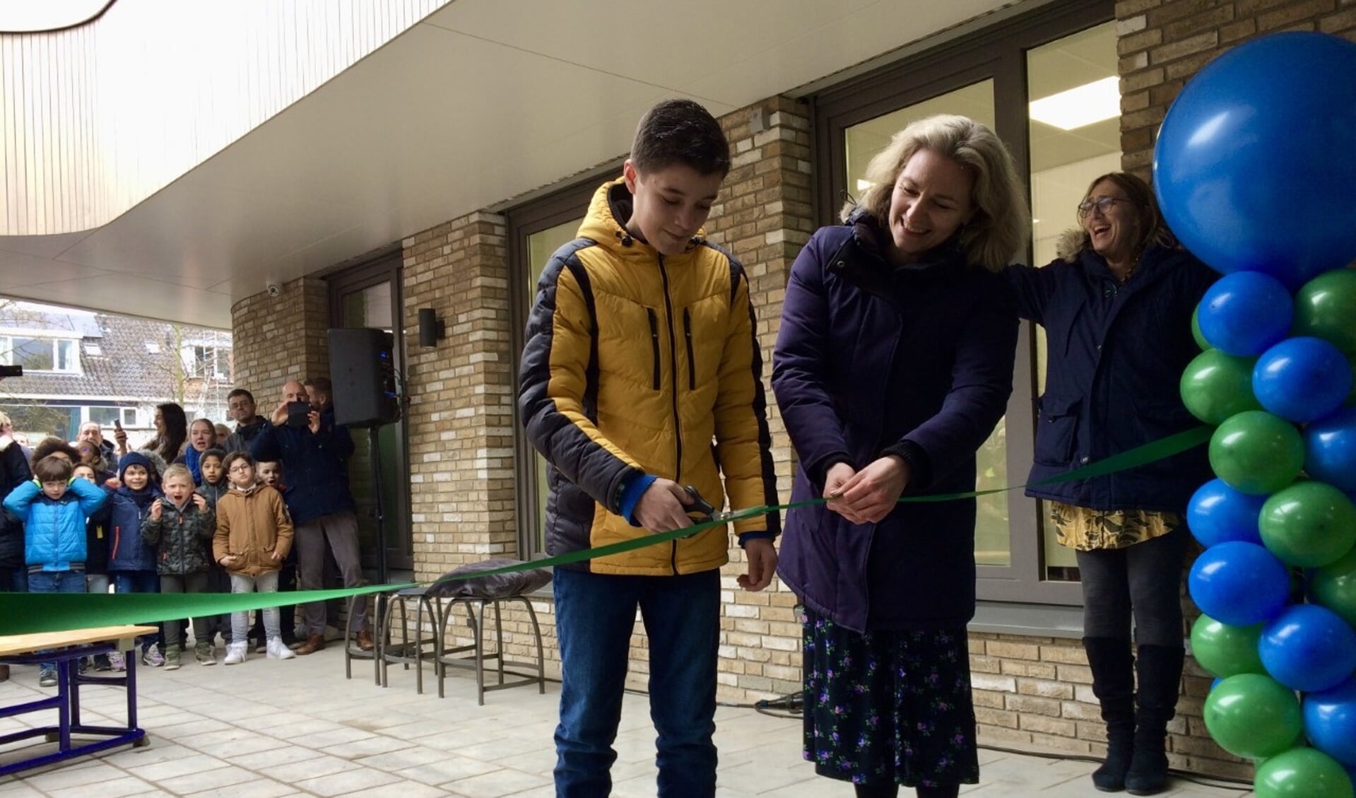 
Jaiden(12)  opent het nieuwe schoolgebouw, geassisteerd door wethouder Anke Klein.