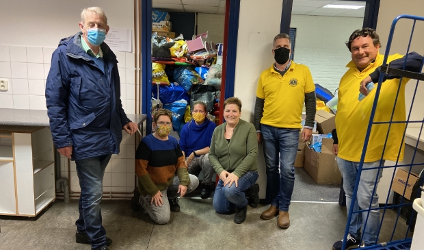 <p>de vrijwilligers van de Speelgoedbank en de Lions, met achter hen de voorraad speelgoed</p>