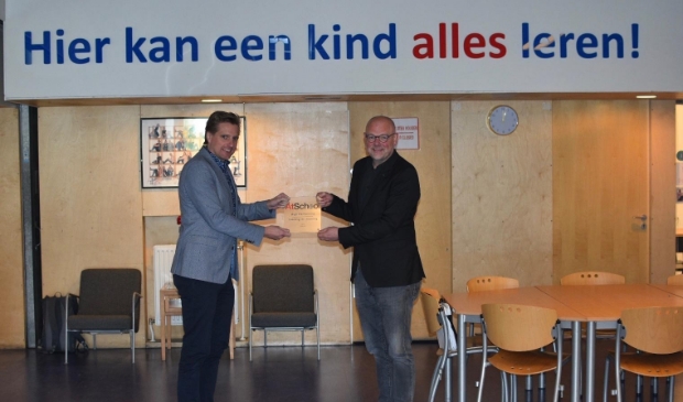 Michel Freriks van CBE Academica overhandigt de bronzen status van 'At School' over aan Maurice Boonstra, directeur KBS Het Veldhuis