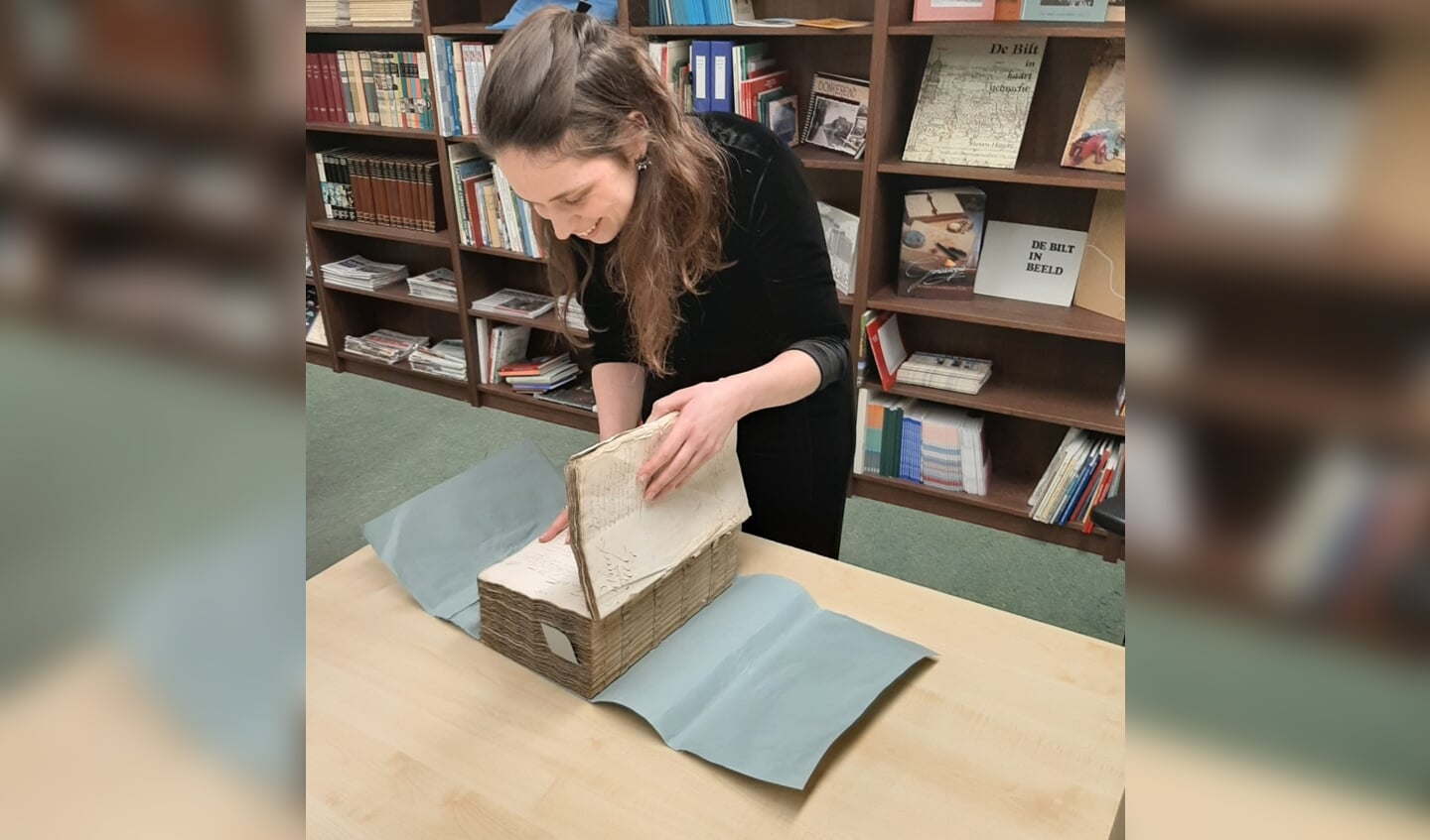 Medewerkster Suzanne Lekkerkerker bladert door een 17e eeuws boek.