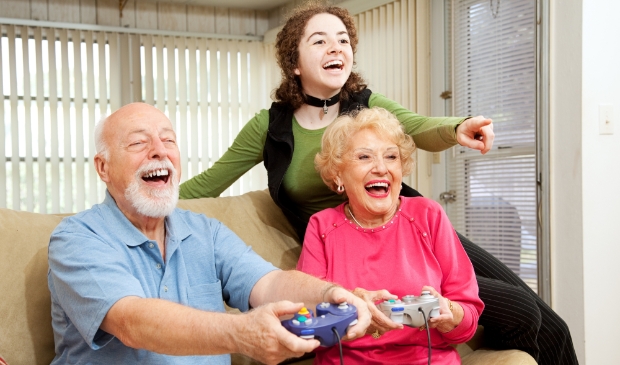 <p>Grandparents and teen girl having fun playing video games.</p>