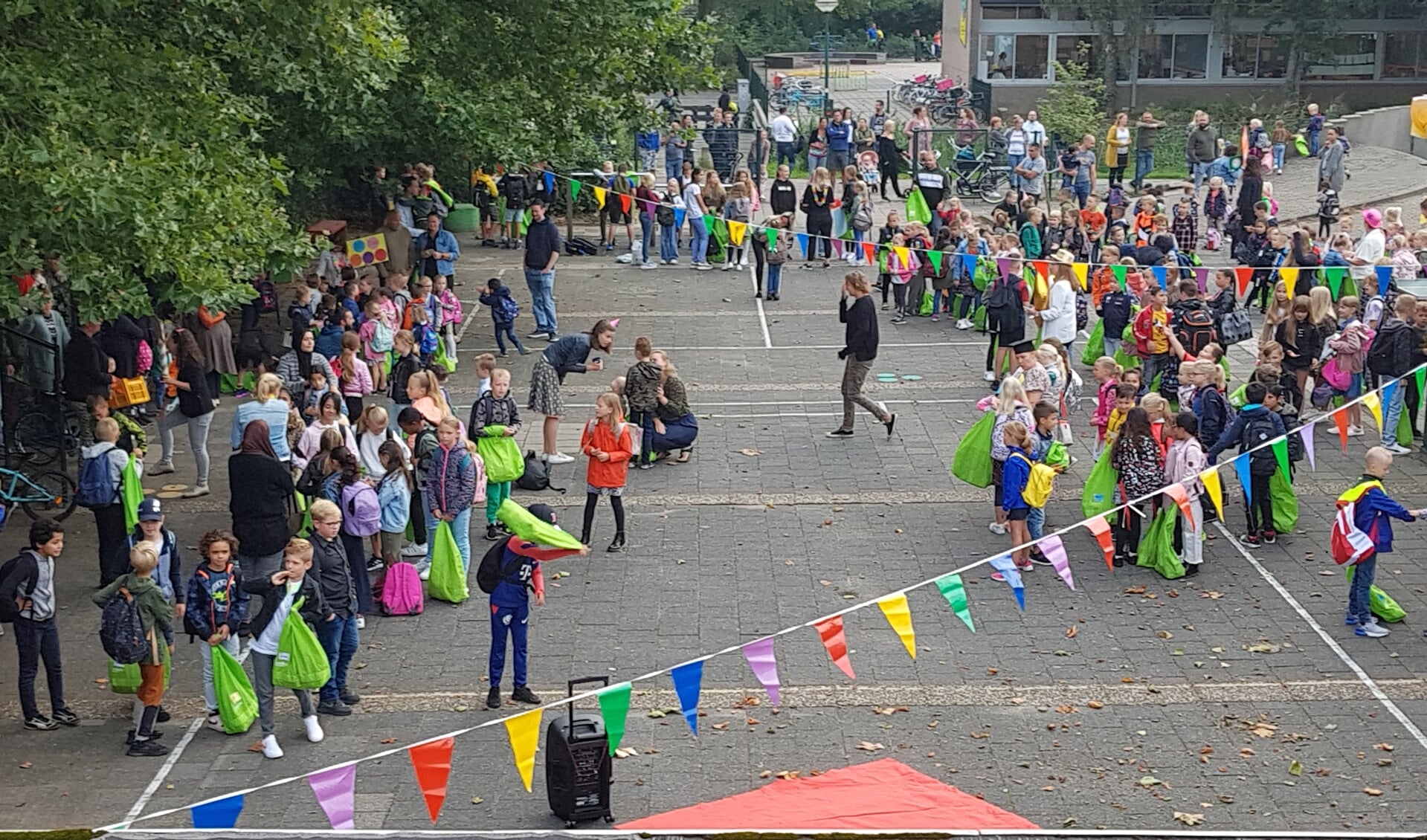 veel kinderen met de ouders op afstand buiten het hek. 