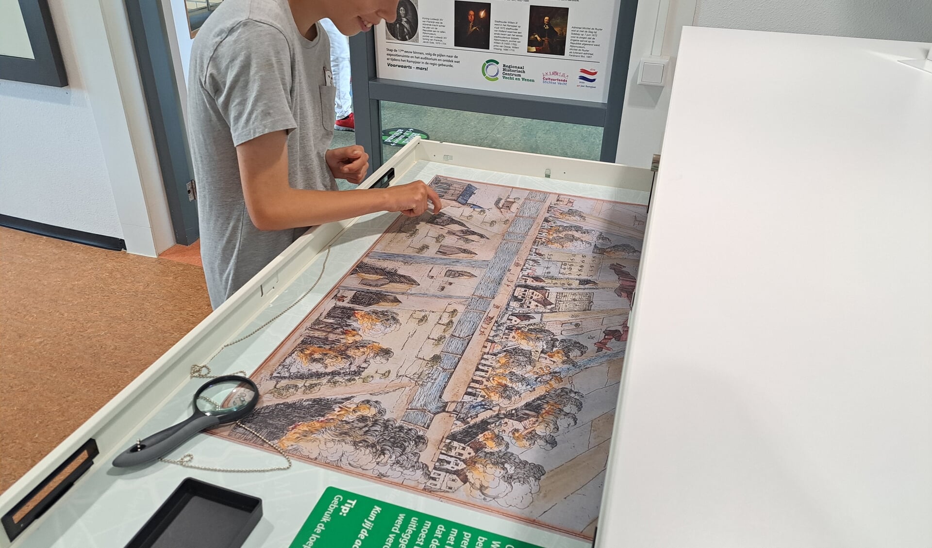 Jonge bezoeker lost een zoekpuzzel op in de tentoonstelling 'Soldaten in de Streek 1672-1673'
