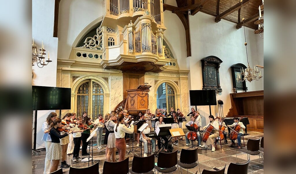 De leden van de Kindersymfonie uit Loenen aan de Vecht en het Benjamin Jeugd Strijkorkest uit Zwolle tijdens hun gezamenlijke optreden in de Grote Kerk in Loenen.