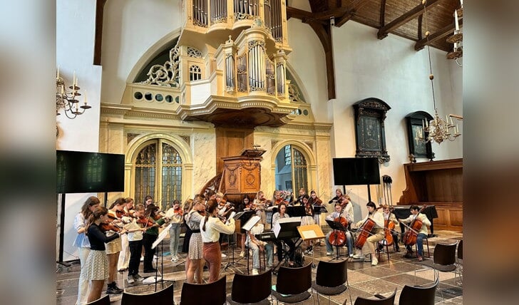 De leden van de Kindersymfonie uit Loenen aan de Vecht en het Benjamin Jeugd Strijkorkest uit Zwolle tijdens hun gezamenlijke optreden in de Grote Kerk in Loenen.
