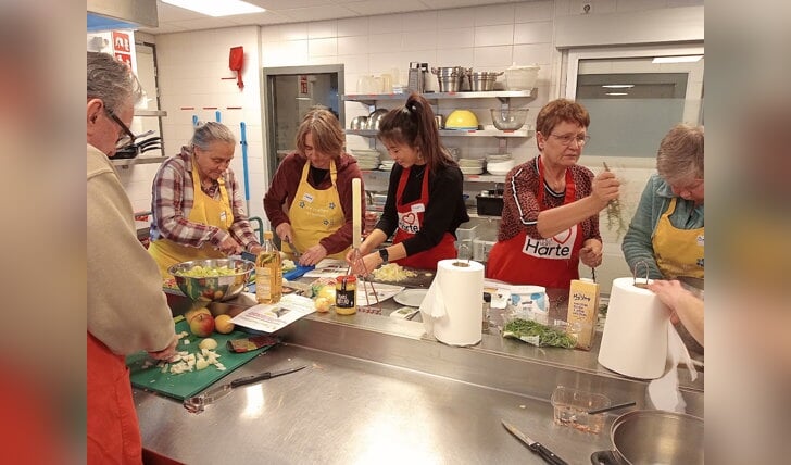 deelnemers en vrijwlligers aan het werk in de keuken