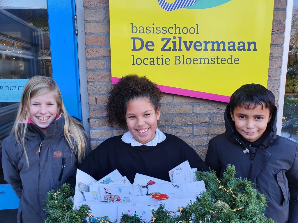 Tirza, Yasser en Kensi van de leerlingenraad van De Zilvermaan met een mand vol zelfgemaakte kerstkaarten