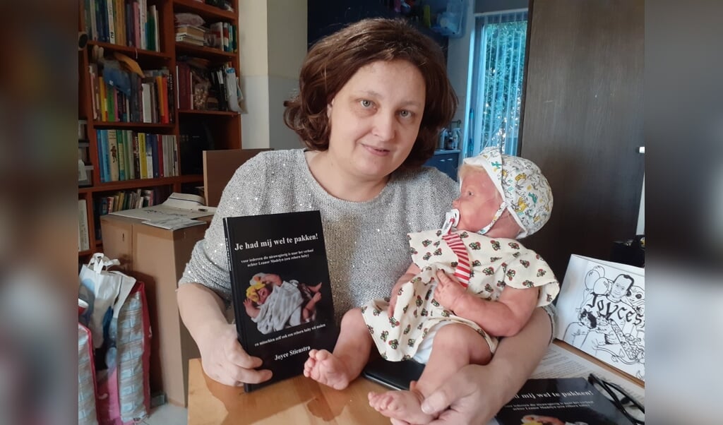 Joyce Stienstra met boek en haar reborn baby.