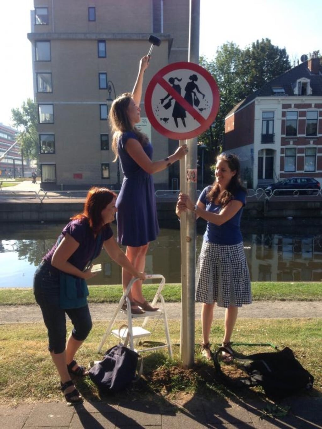 PvdD-raadslid Eva van Esch plaatst een bord op de Timorkade samen met fractiemedewerkers Saskia en Anne 