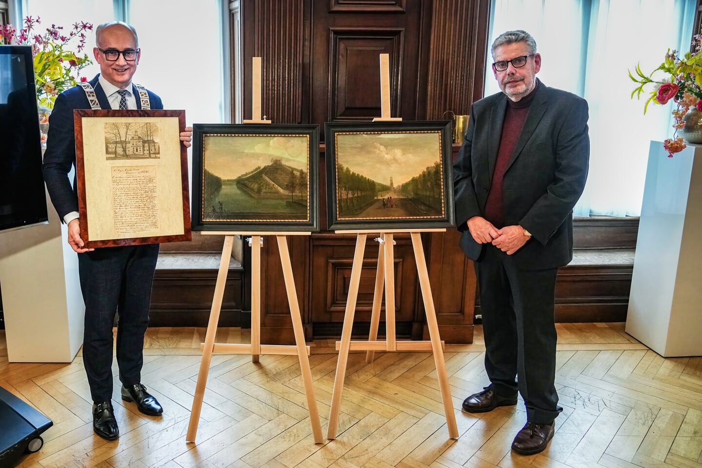 Burgemeester Fred Veenstra en Alexander Langhout naast de schilderijen. 