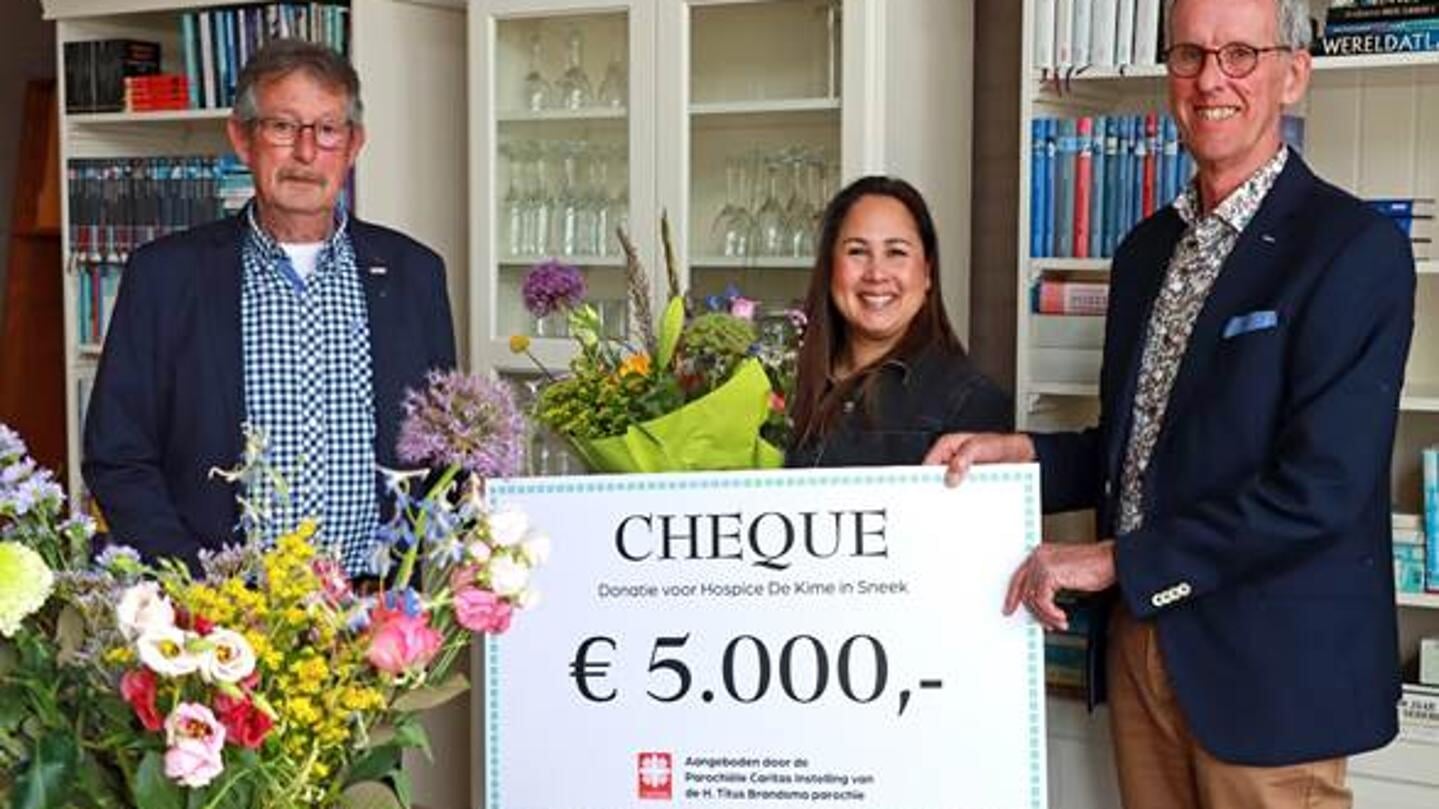 Op de foto wordt de cheque door voorzitter Bouwe Rijpma (r) en penningmeester Tjebbe Witteveen (l) van de Caritas overhandigd aan Corrie Karsters, coördinator van Hospice De Kime.
