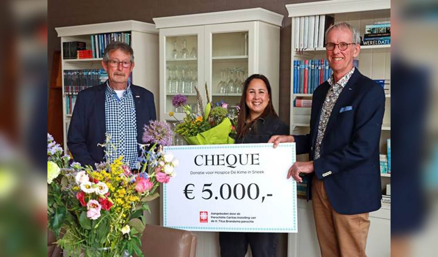 Op de foto wordt de cheque door voorzitter Bouwe Rijpma (r) en penningmeester Tjebbe Witteveen (l) van de Caritas overhandigd aan Corrie Karsters, coördinator van Hospice De Kime