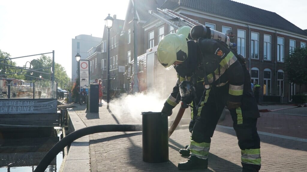 De brandweer blust de brand in de prullenbak. 