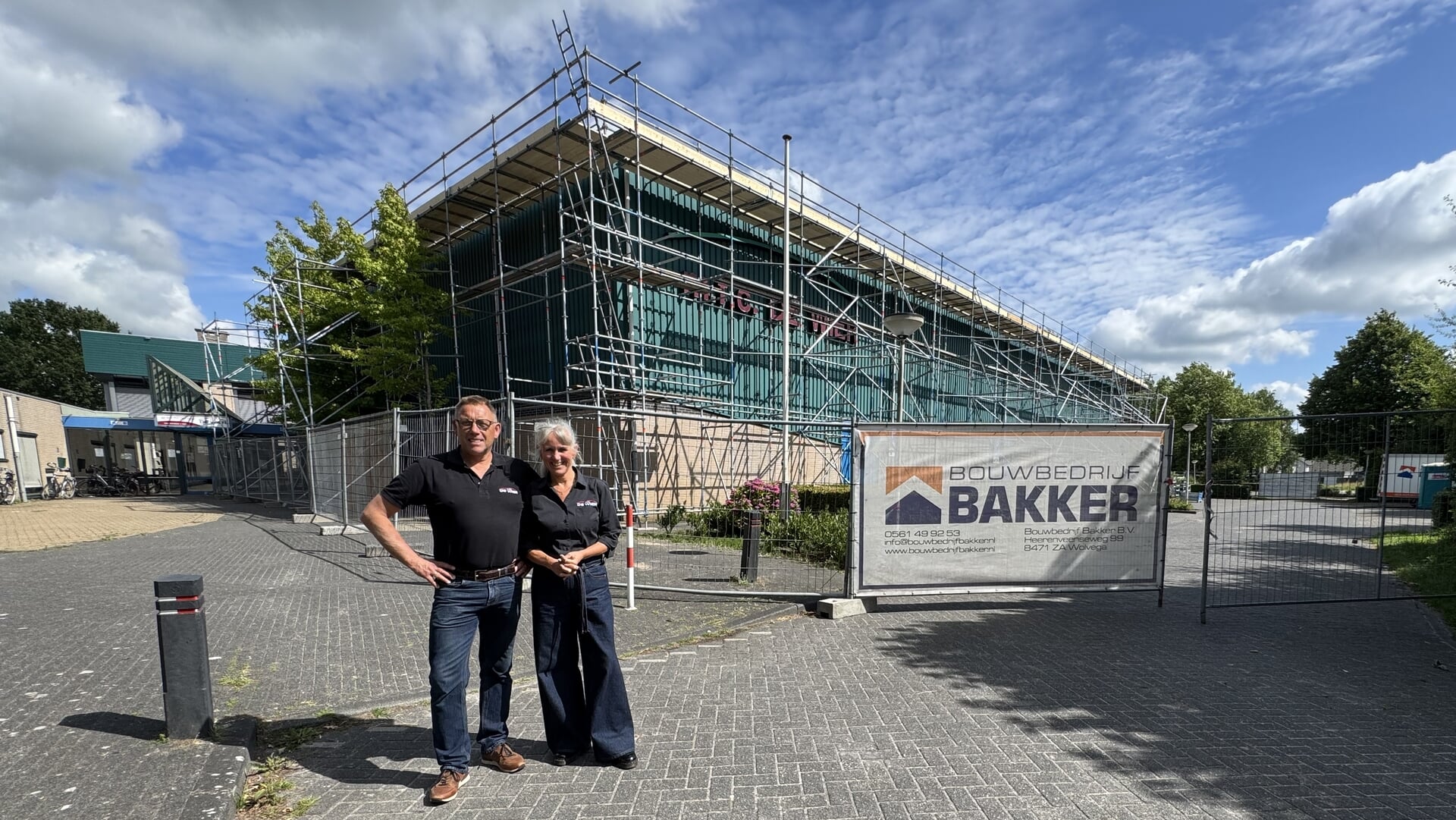 Het beheerdersechtpaar Henk en Grytsje de Jong poseert voor de sporthal van MFC De Wier waarvan maandag wordt gestart met de renovatie van het dak