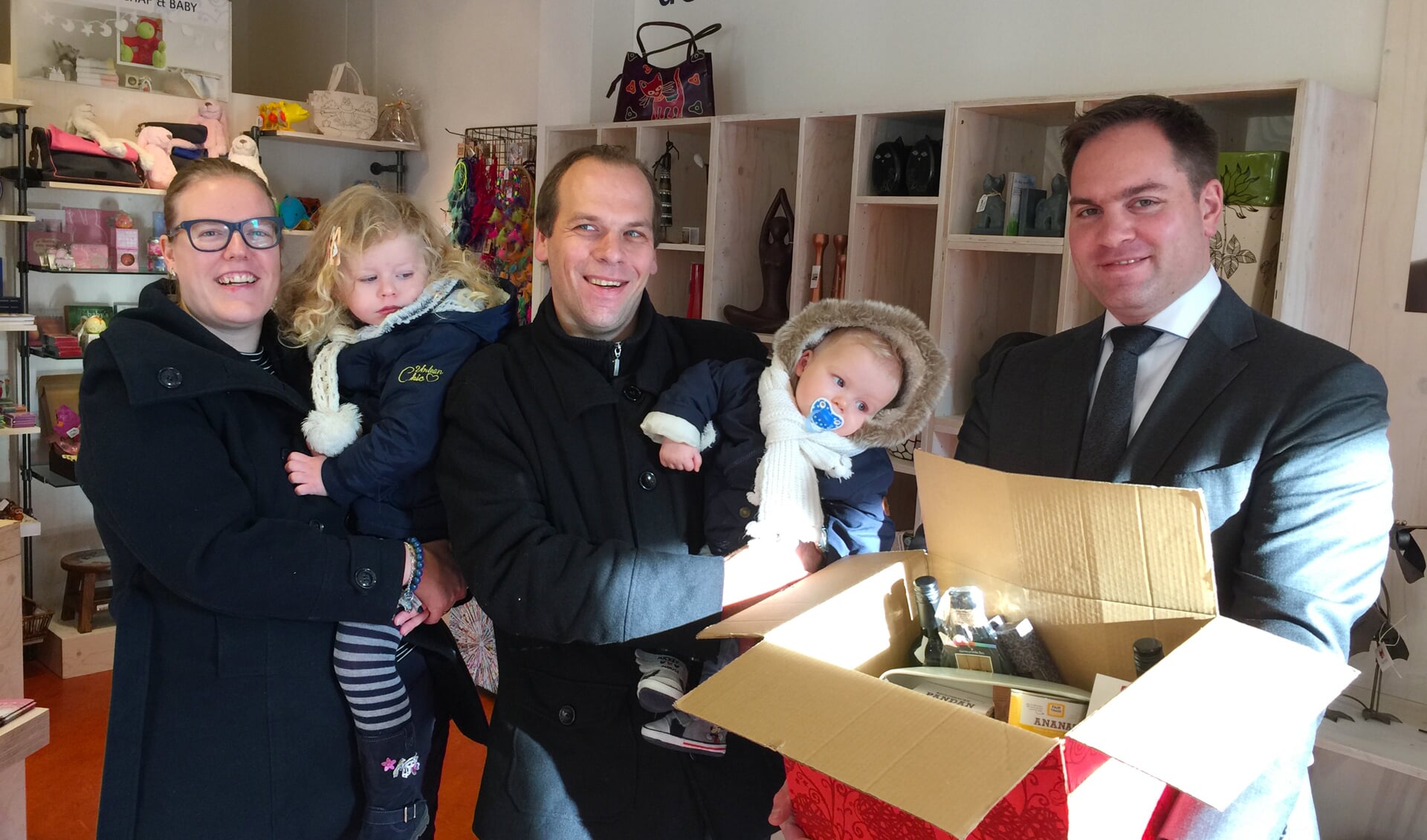 Freek van der Valk overhandigt het Wereldwinkel kerstpakket van deze week aan winnaar Gerrit Boer, vergezeld van zijn vrouw Veronique, dochtertje Eloisa en zoontje Eliano.