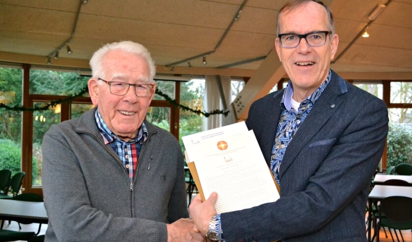 Foto: Kees Vos, voorzitter van de wijkkerkenraad, overhandigt de oorkonde aan Wim Mes.
