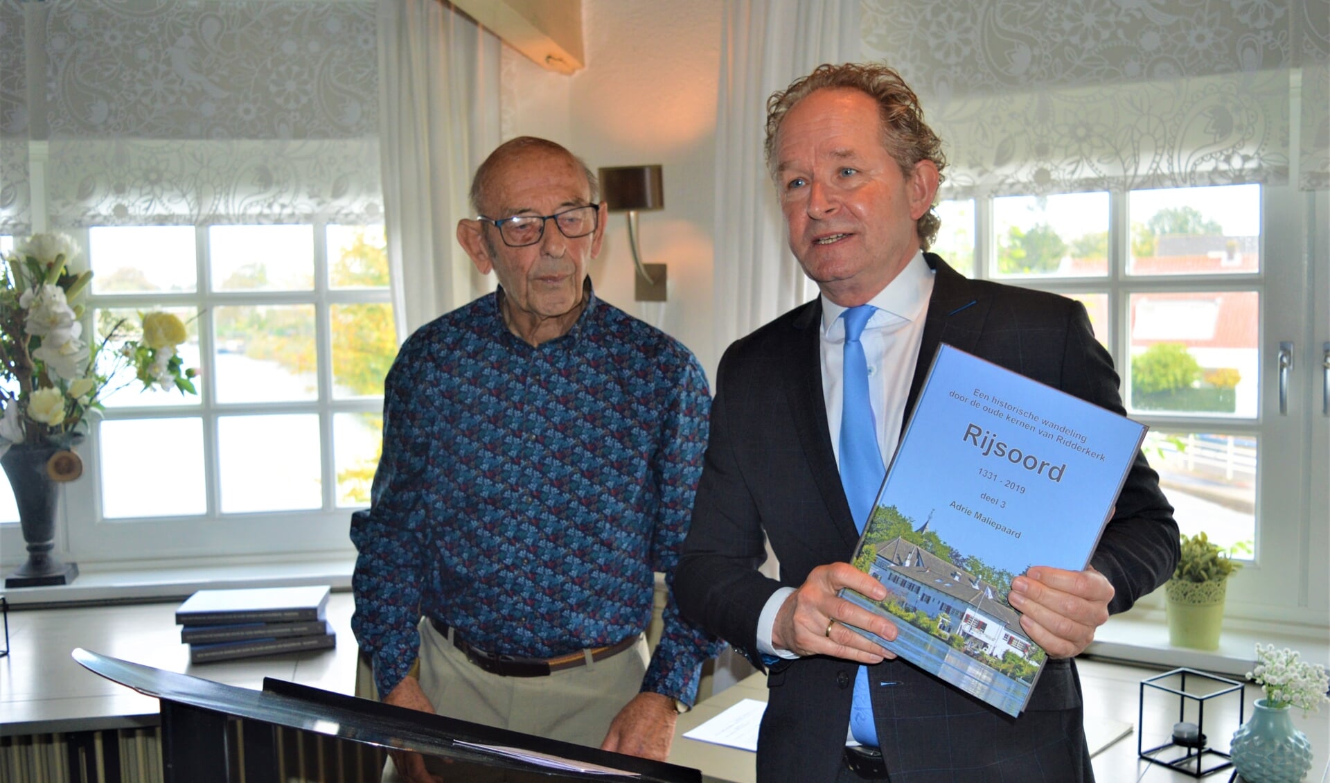 Wethouder Japenga prees met het boek in handen Adrie Maliepaard