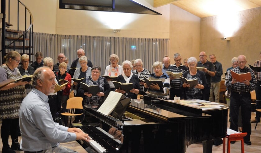 Dirigent Hans Cok achter de piano bij een koorrepetitie
