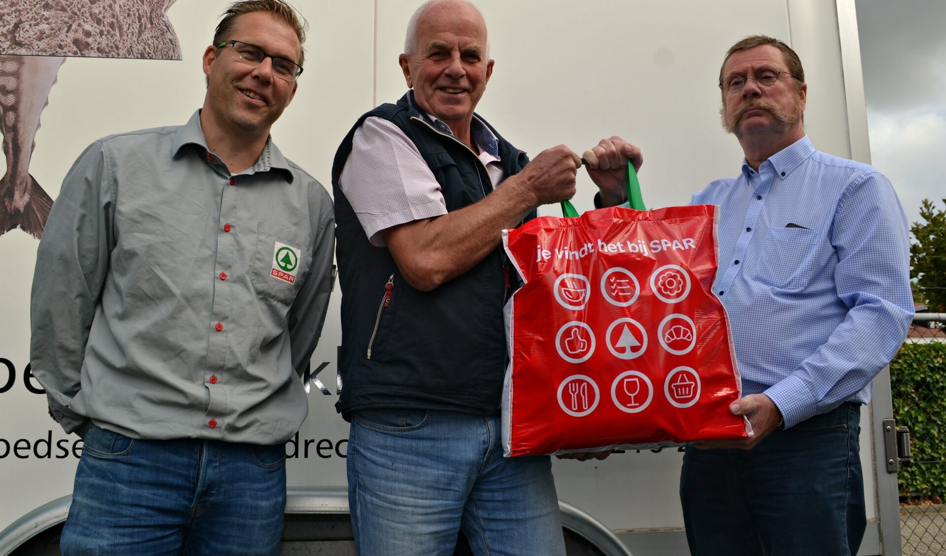 Jack Limburg (rechts) overhandigt het eerste pakket aan Andries van Die van de Voedselbank Barendrecht. Links Remco Klootwijk.