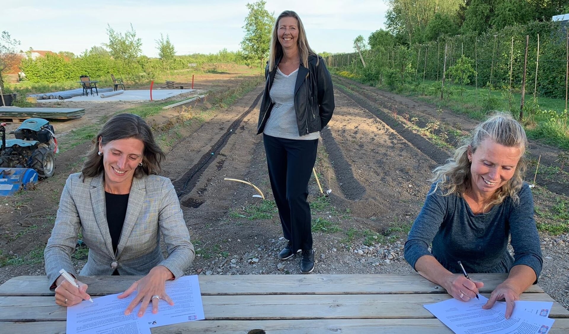 Ingrid Hartog (links) en Claudia Reijnen tekenen de samenwerkingsovereenkomst. Linda Sanders kijkt toe.