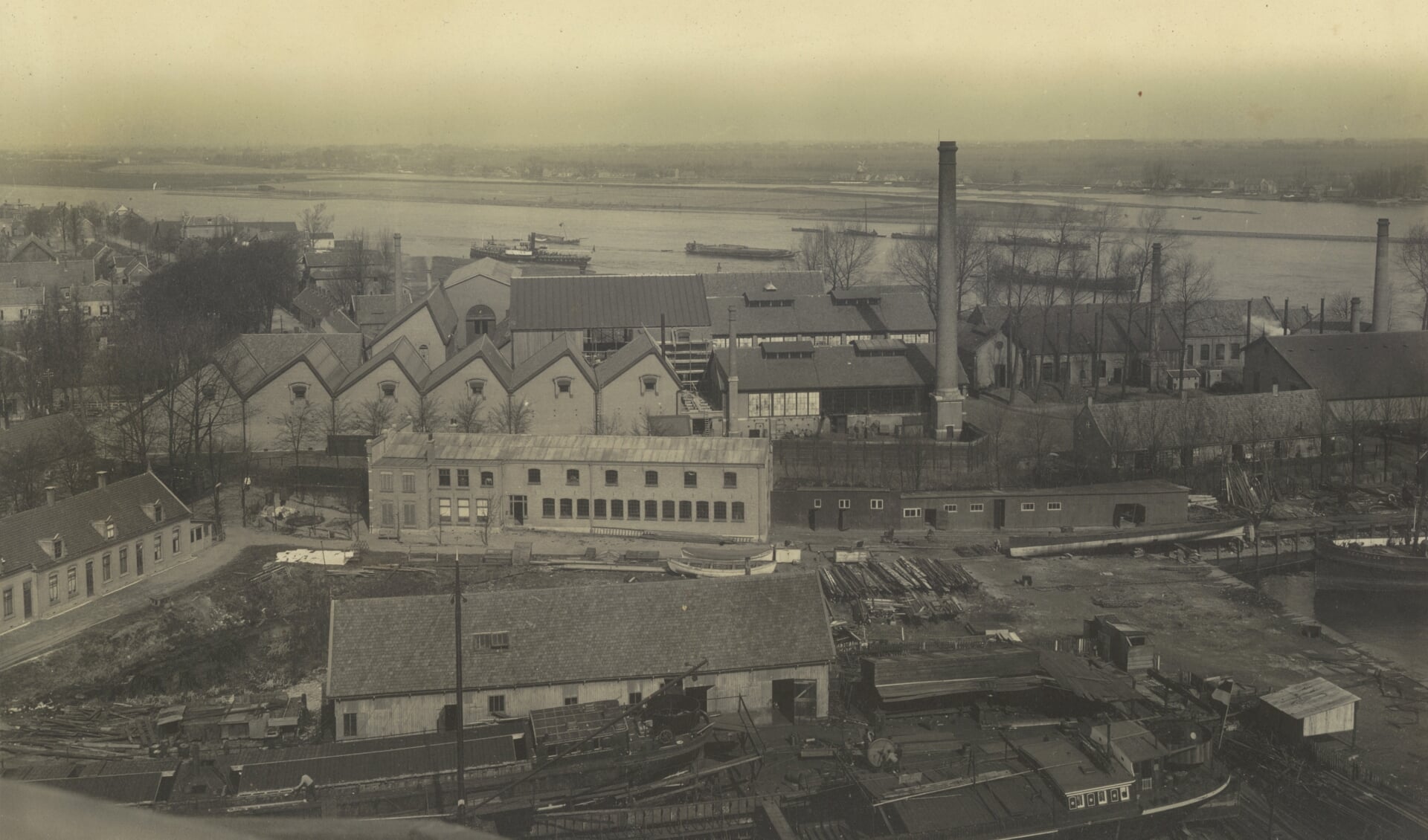 De werf van De Groot & Van Vliet rond 1910 met daarachter de gebouwen van Smit Slikkerveer