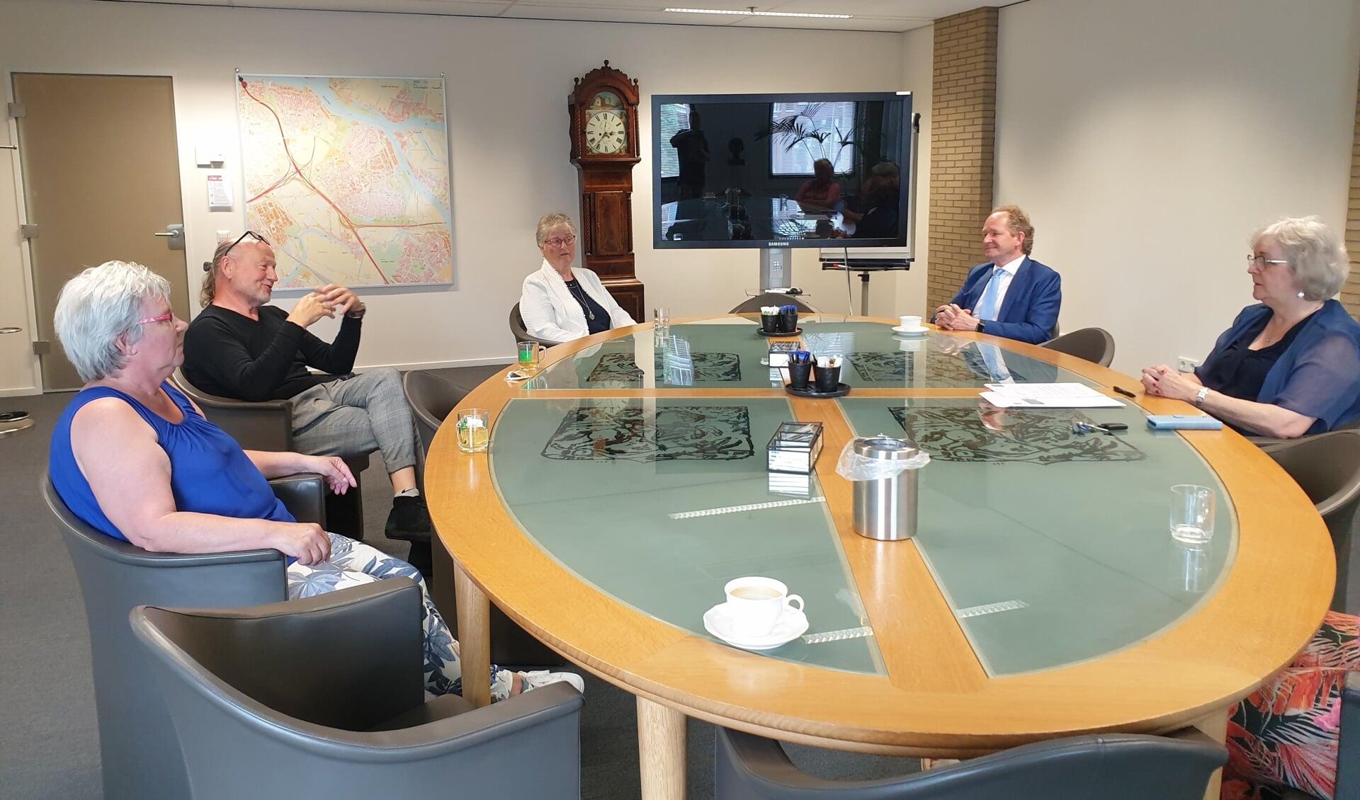 Bestuursleden van Stichting Wijkactiviteiten Slikkerveer rond de tafel met burgemeester Anny Attema en wethouder Marten Japenga