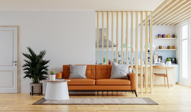 Living room interior wall mockup in warm tones with leather sofa which is behind the kitchen.3d rendering