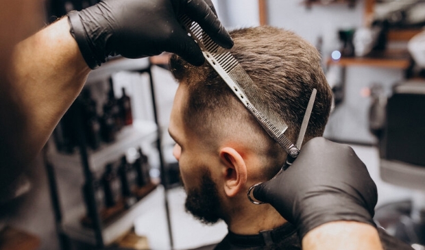 Client doing hair cut at a barber shop salon 