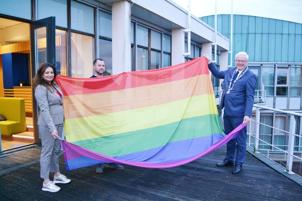 Wethouder, jongerenwerker en burgemeester met de regenboogvlag.