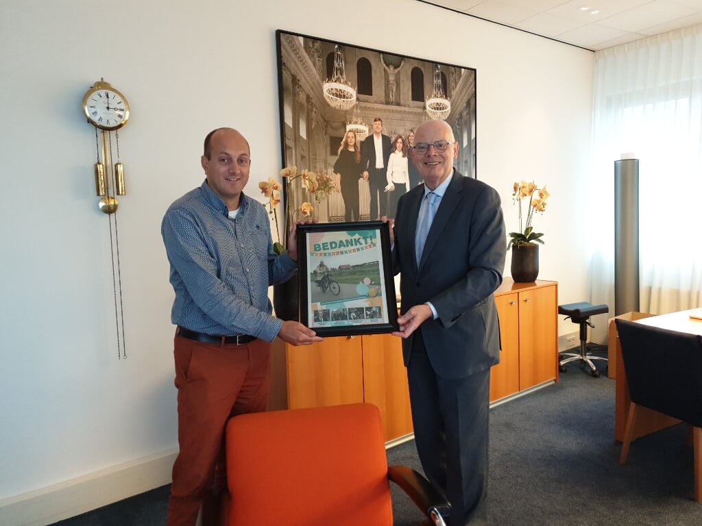 Willem Monteban overhandigt de ingelijste krant aan burgemeester Jan van Belzen. 