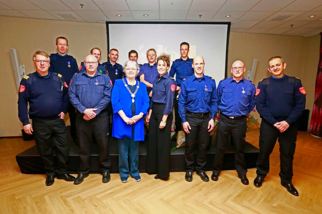 De burgemeester met brandweerkrachten die oorkondes en diploma's ontvingen