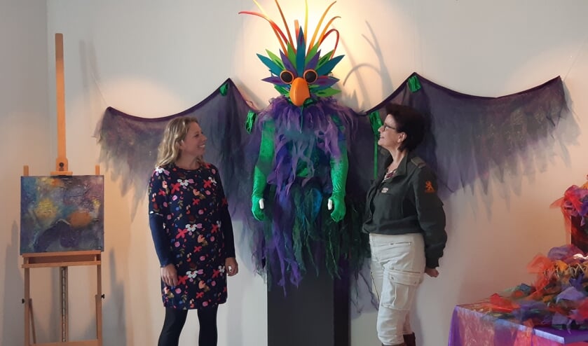 <p>Dorien (rechts) en Willemien bij een van de kostuums. Rechts in de hoek het schilderij van Roos.</p>