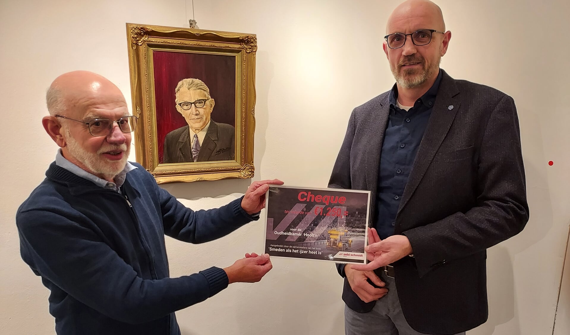 Patrick Schothuis (r) overhandigd de cheque aan Gerrit te Winkel. Op de achtergrond het schilderij van Herman Klein Velderman.