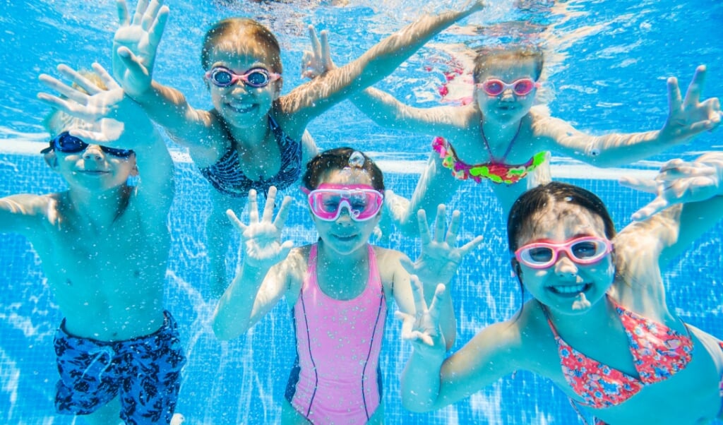 Parelduiken, kokosnootraces, limbo-dansen, vrij zwemmen en nog veel meer: kinderen vermaken zich volop in zwembad De Vlaskoel. 