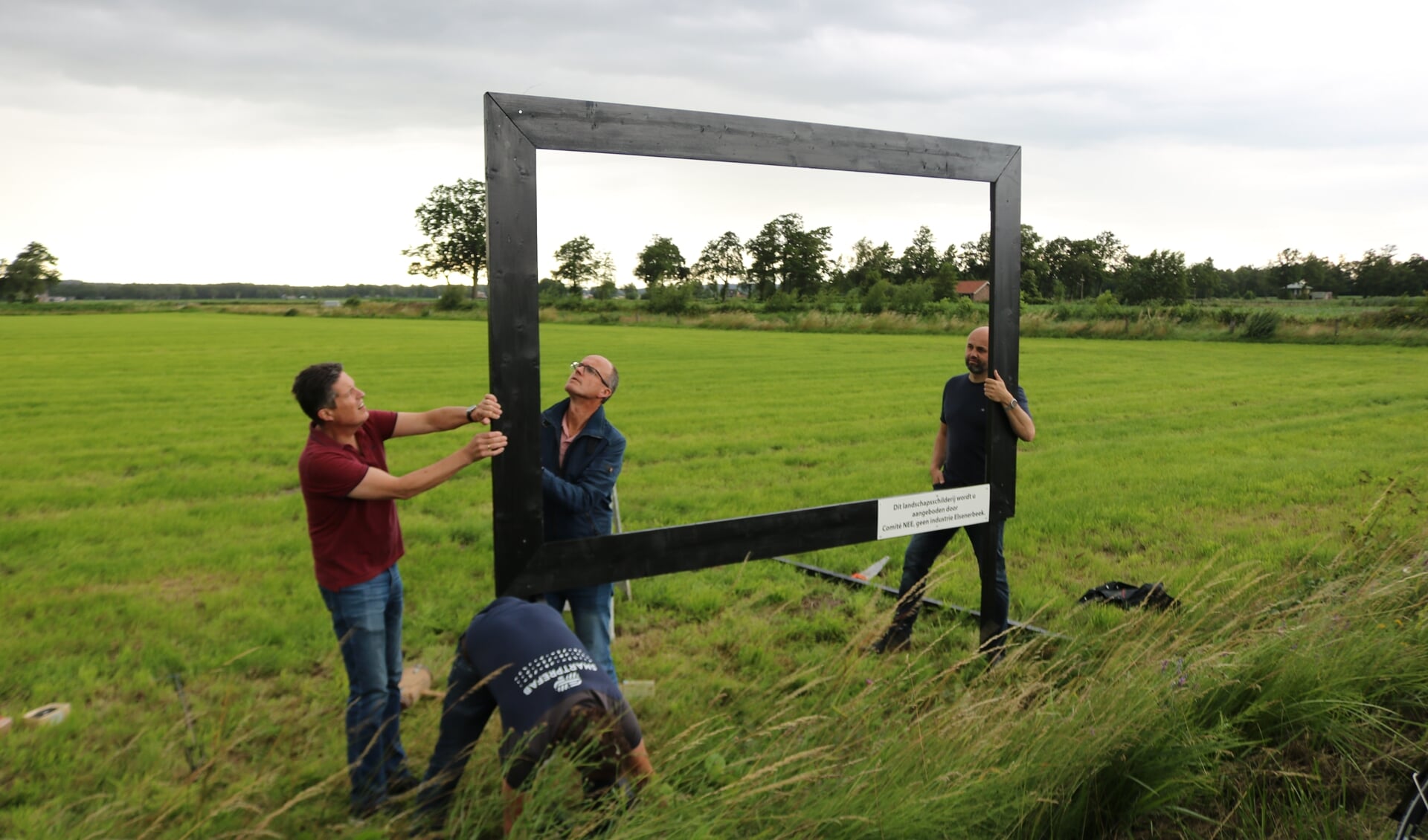 Leden van het actiecomité geen industrie in Elsenerbeek plaatsen het landschapsschilderij. Binnen de lijst links Gert-Jan Geerling (links) en Leo Nieuwenhuis.  