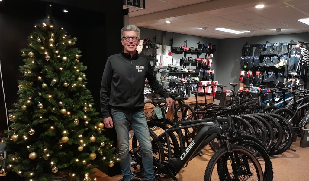 Erik Baan heeft voor het eerst ruimte om een kerstboom in de winkel te zetten. Trots poseert hij bij de nieuwe Cube-fietsen.