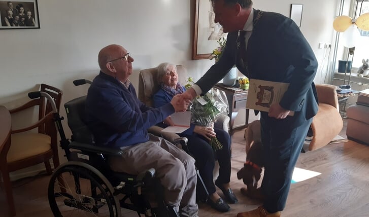 Burgemeester Jorrit Eijbersen feliciteert het echtpaar. In zijn hand houdt hij nog de oorspronkelijke trouwakte, die hij later zal overhandigen.