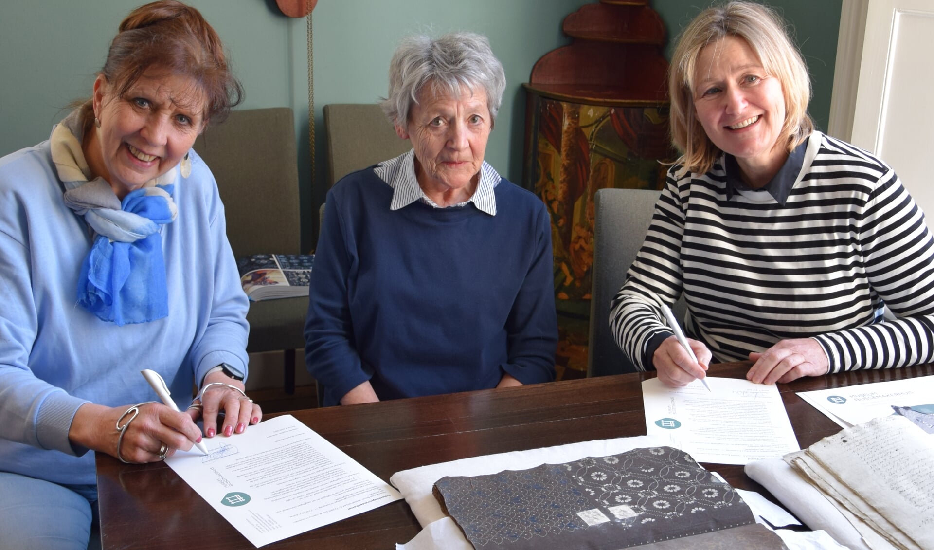 Annemarie Haak(Heemkunde) en Liesbeth Hassink(Bussemakerhuis) ondertekenen de overdracht. Thea Schoemaker Mulder kijkt toe.