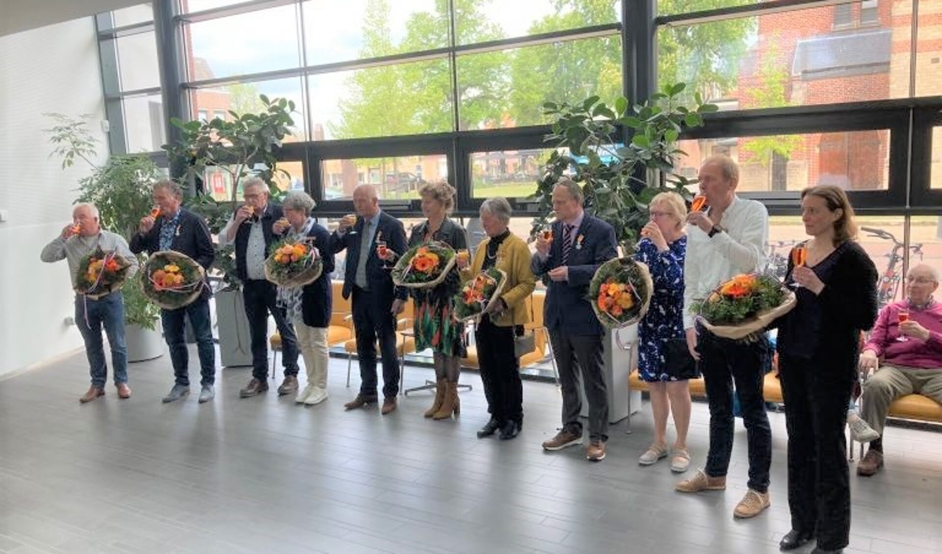 De gedecoreerden van Rijssen, Holten en Wierden brengen een toost uit op hun onderscheiding in de hal van de gemeentehuis in Rijssen. 