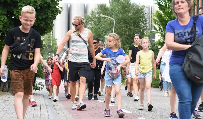 Ouders en kinderen doen mee aan de avondvierdaagse en passeren hier het Rijssense bedrijventerrein.  