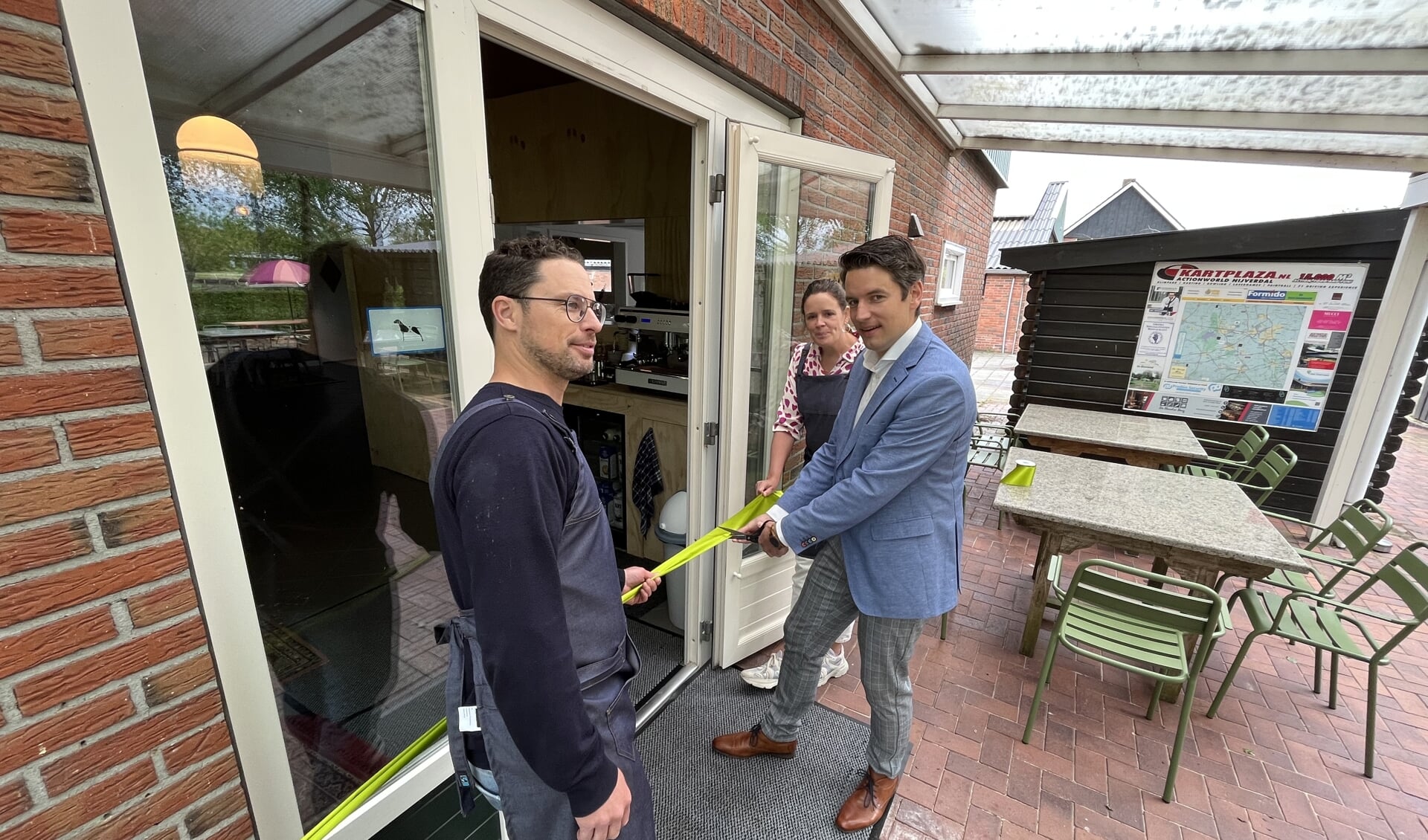 Wethouder Erik Wessels (midden) knipt het lint door van het nieuwe restaurant van Buiteninn Het Overveen. Rechts bedrijfsleidster Linde Nieuwenhuis en links horeca-adviseur Ralph Sturkenboom.