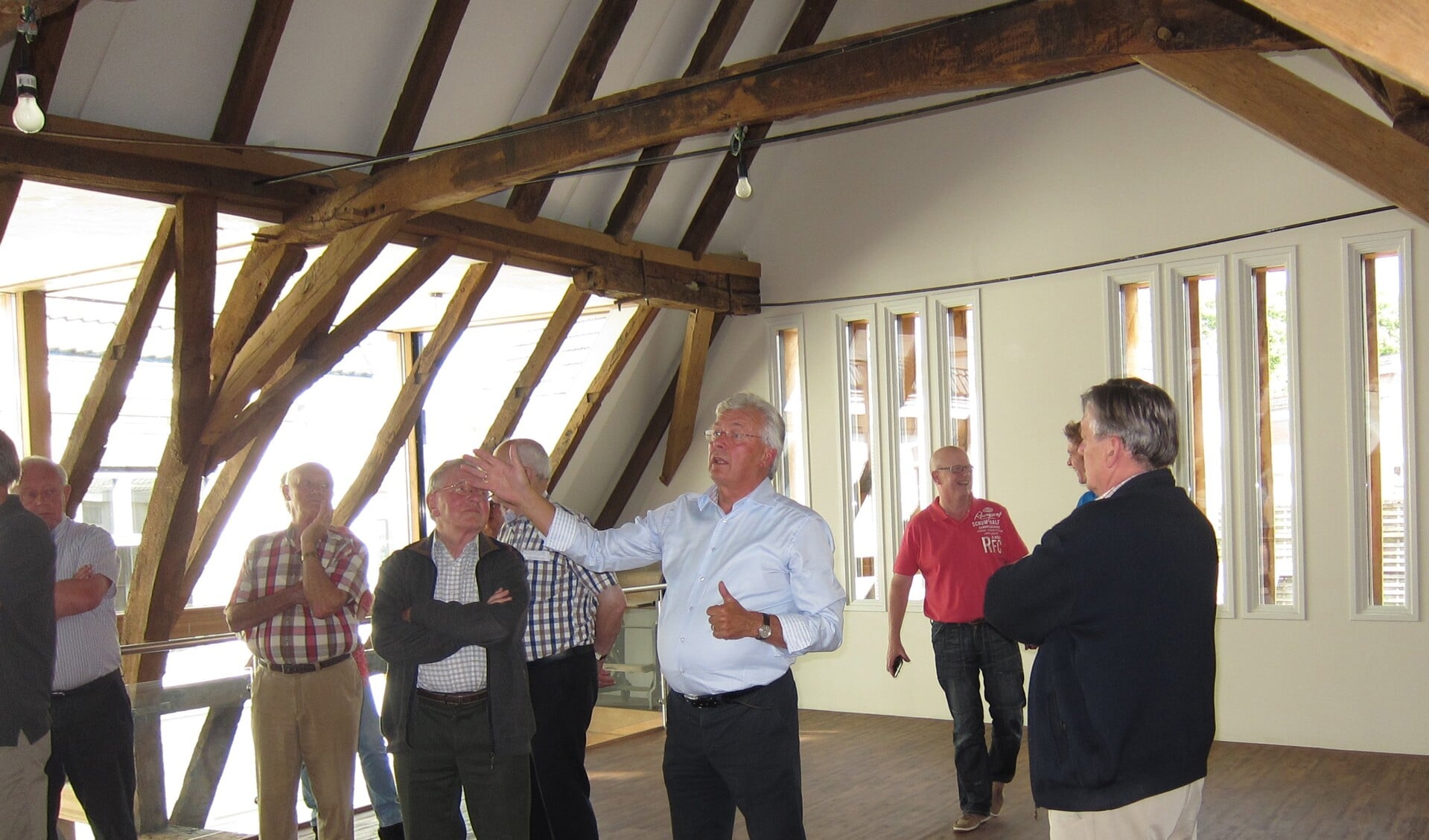 Henk Wolterink (midden) geeft een rondleiding door de Stadsboerderij. Hier vertelt hij de Twentse schrijvers in de bovenzaal over de kapconstructie.  