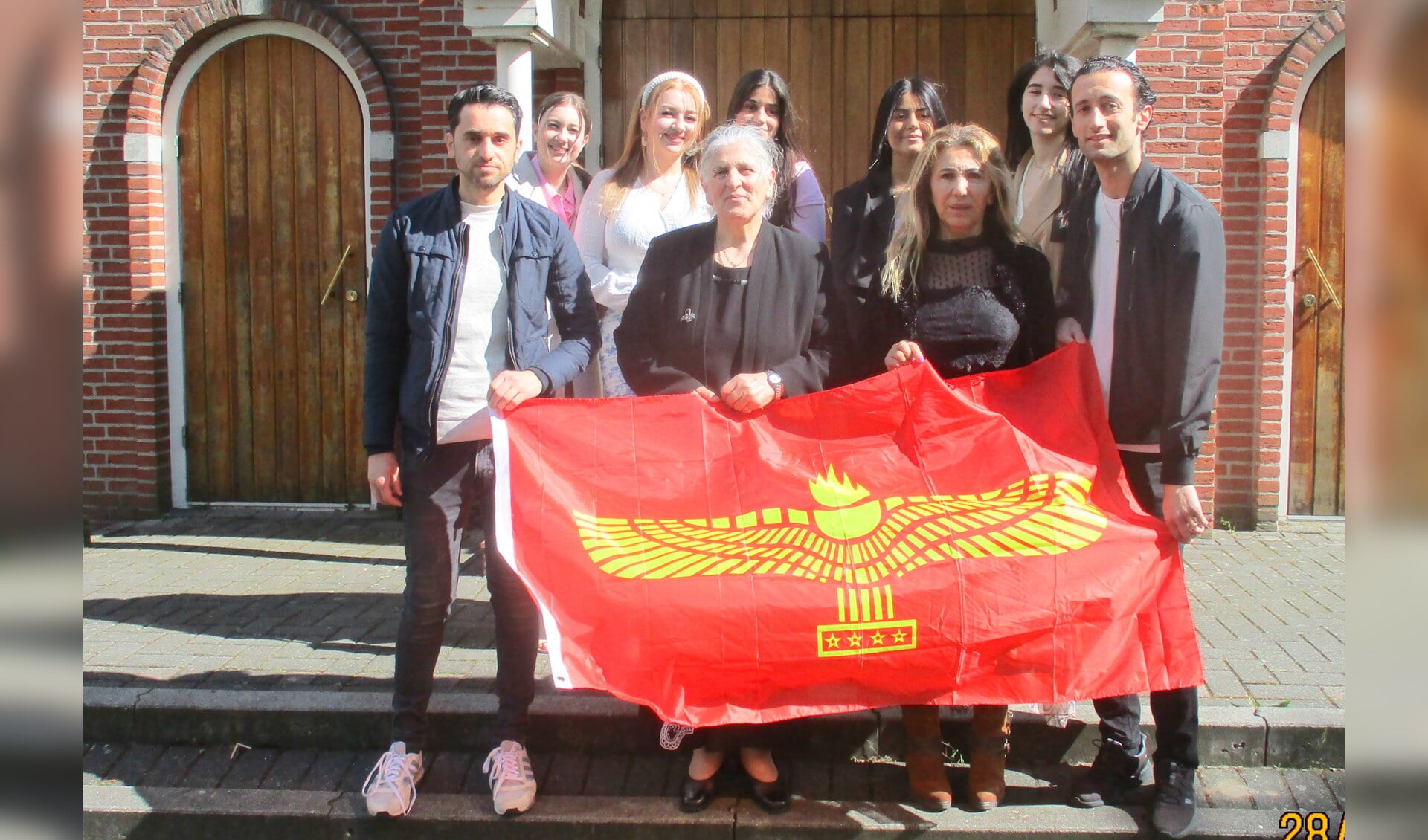 Het Syrisch Orthodox vrouwenkoor Oldenzaal zal ook optreden. Ze houden de Aramese vlag vast. (Tekst/foto: Martin Meijerink)